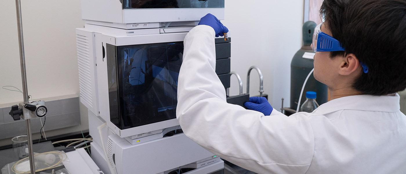 Chemistry student examining substance in a tube removed from lab equipment